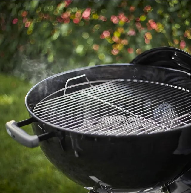 Parrilla redonda con carbón en el jardín