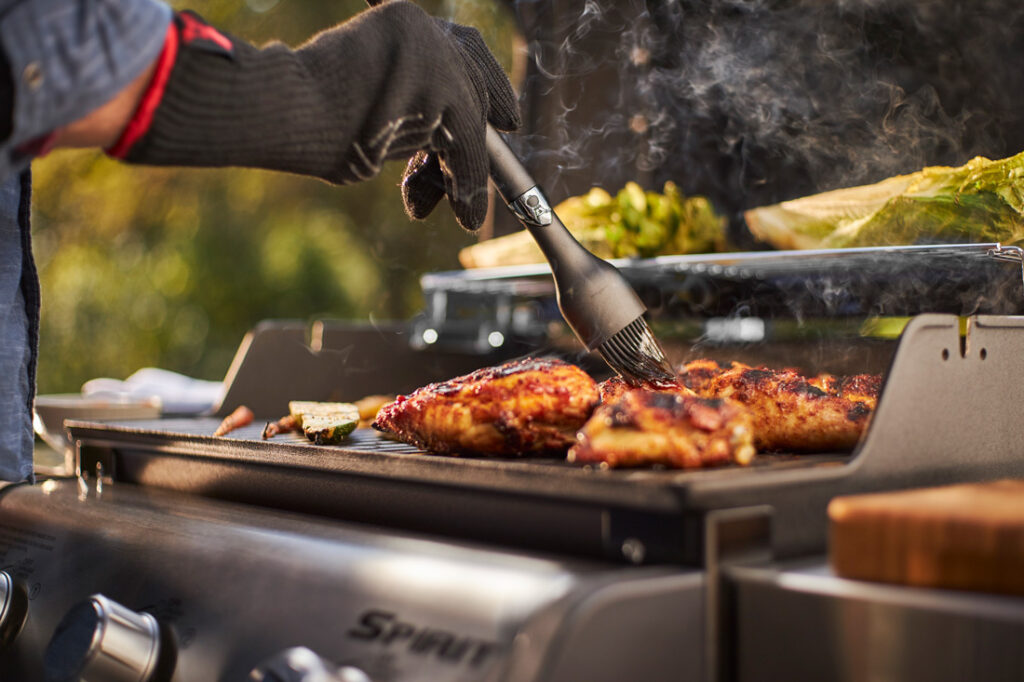 Asando pollo a la parrilla con guante protector.