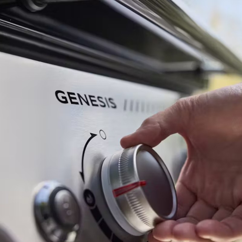Mano ajustando perilla de barbacoa Genesis