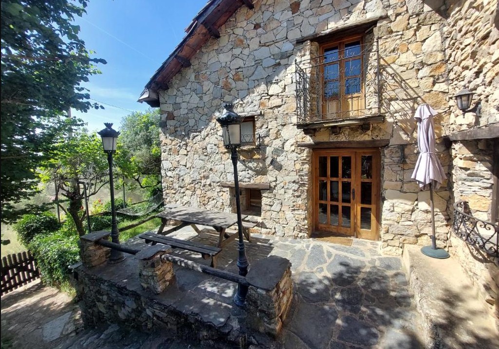 Casa de piedra rústica con terraza exterior.