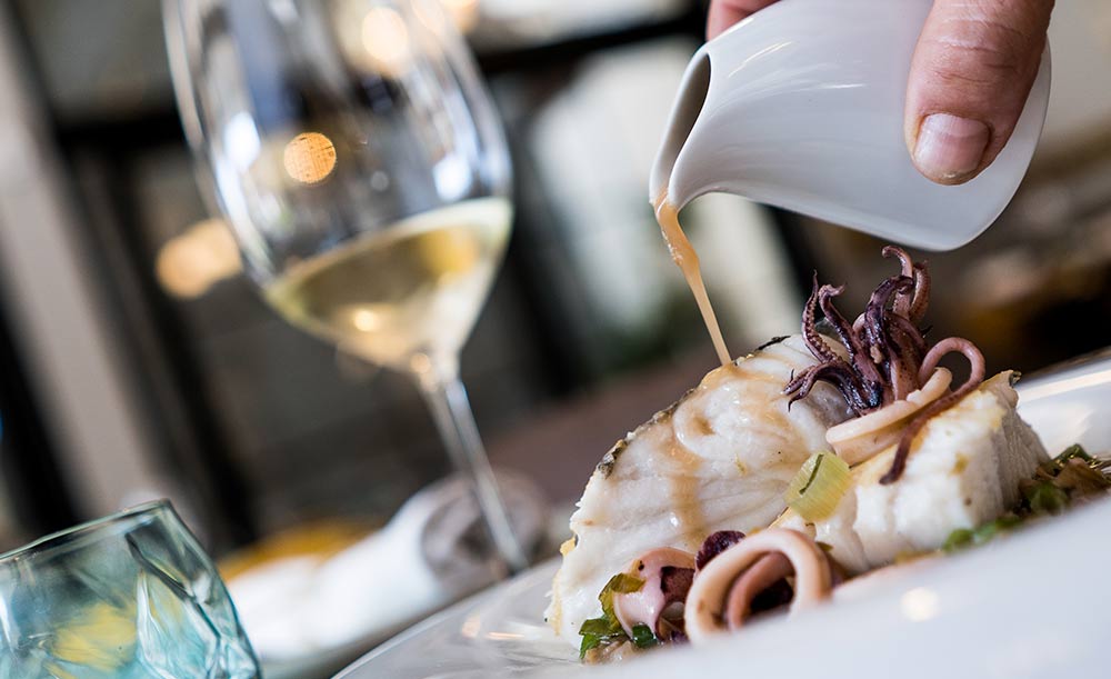Plato de pescado con calamares y vino blanco.