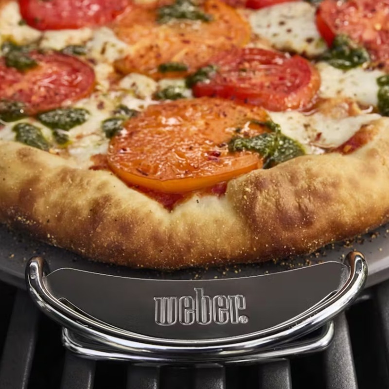 Pizza cocinada en parrilla Weber con tomates y pesto.