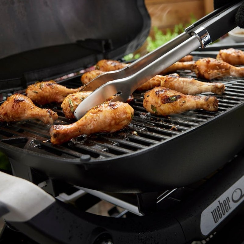 Muslos de pollo asados en barbacoa con pinzas.