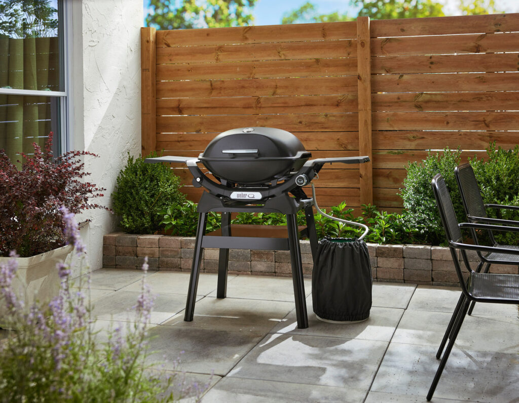 Barbacoa en terraza con sillas y plantas.