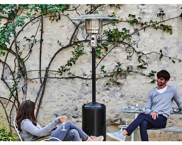 Personas conversando al lado de un calefactor exterior.