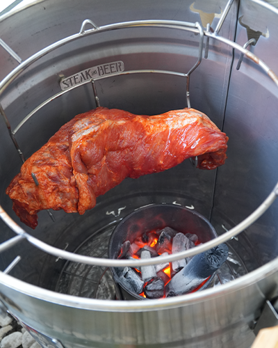 Carne asándose sobre carbón en parrilla abierta.