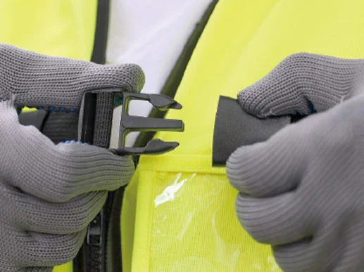 Manos con guantes abrochando chaleco reflectante