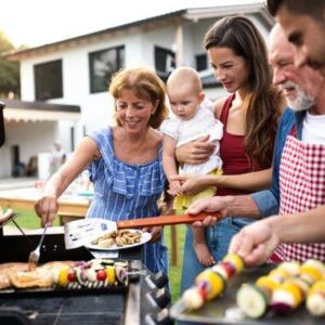 Familia cocinando brochetas en barbacoa al aire libre