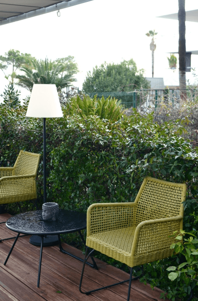 Terraza con sillones verdes y mesa redonda