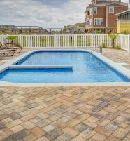 Piscina rectangular en patio con suelo adoquinado