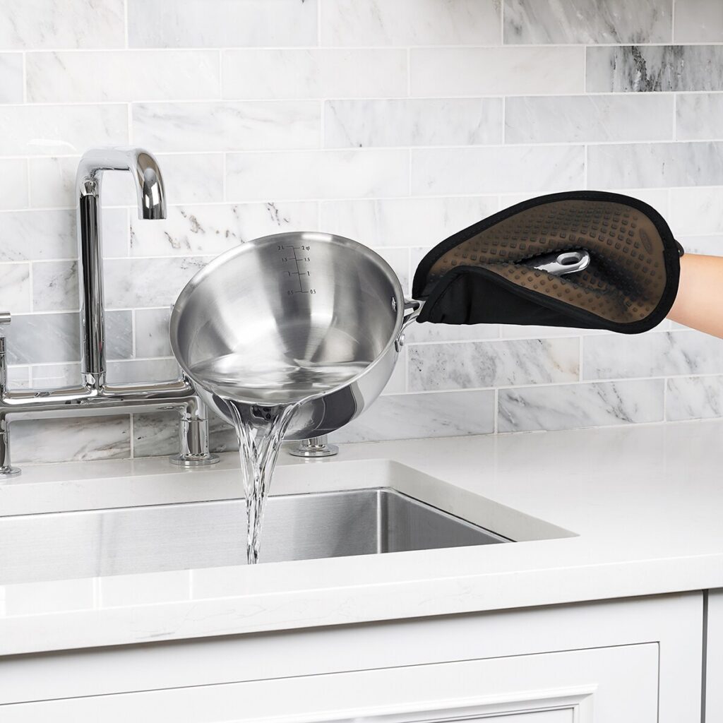 Cazo vertiendo agua en fregadero de cocina